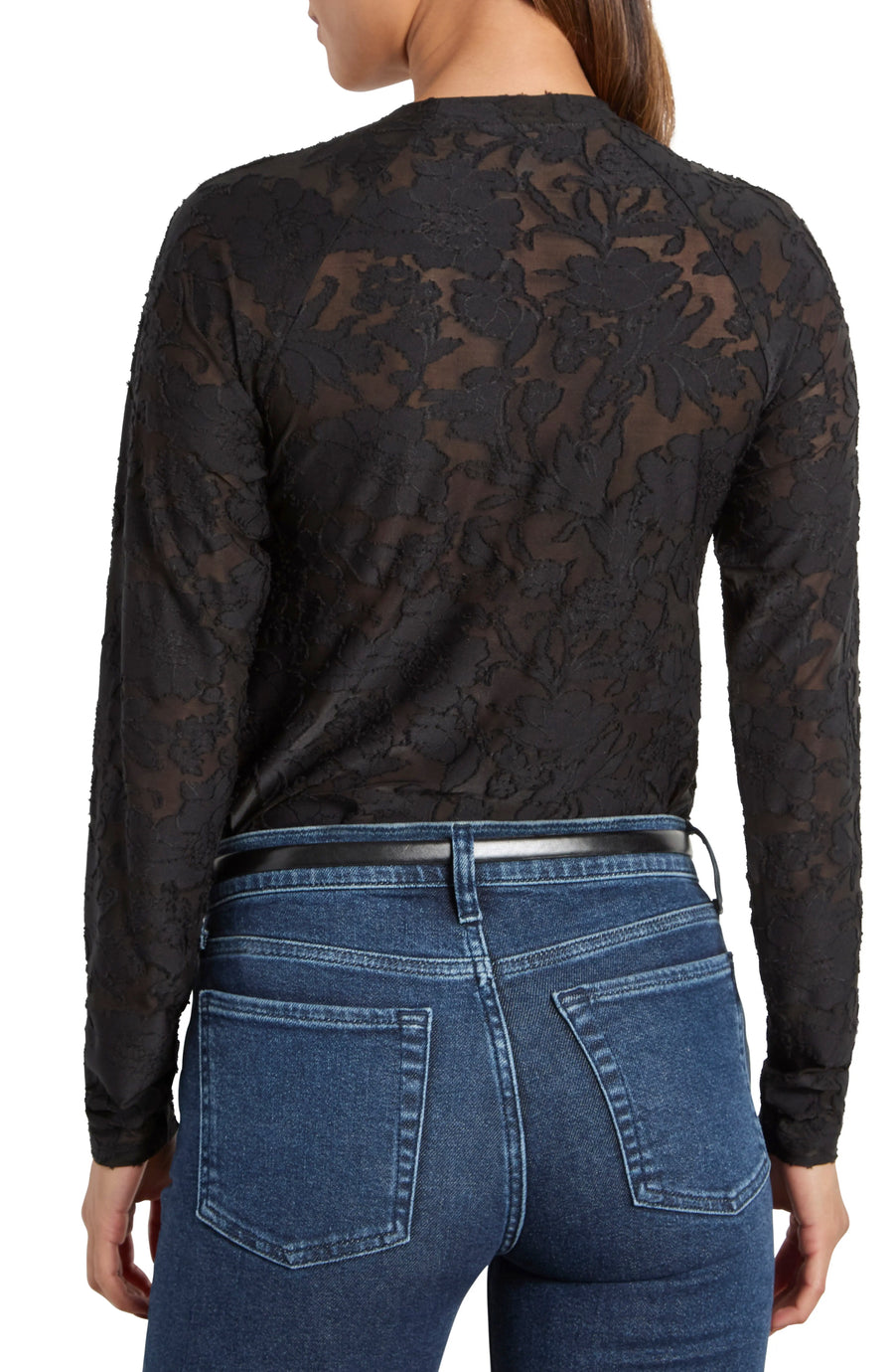 Person wearing a black patterned long-sleeve top and blue jeans on a white background
