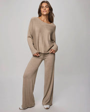 Woman wearing a beige sweater and pants set on a plain background