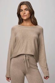 Woman wearing a beige sweater and pants set on a gray background