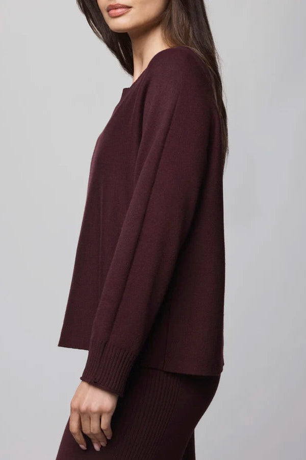 Maroon sweater worn by a person on a gray background