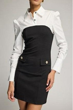 A woman wearing a color-blocked shirt dress with a white long-sleeve button-up collar and shoulders, and a black fitted skirt section with flap pockets and gold-tone buttons, 