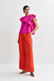Woman wearing a bright pink top with ruffled sleeves, front