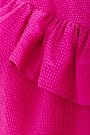 Woman wearing a bright pink top with ruffled sleeves, detail