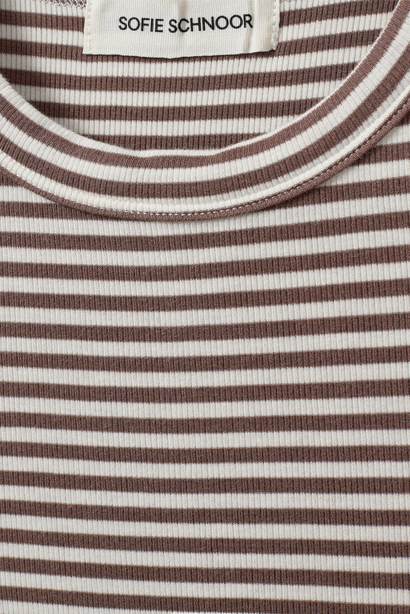Woman wearing a brown and white striped sleeveless tank top with a fitted silhouette, fabric detail