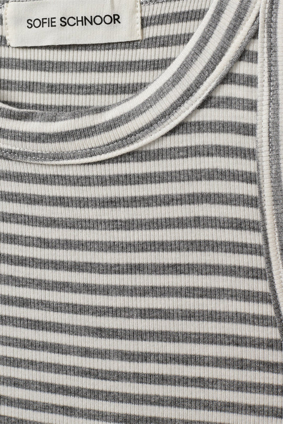 Woman wearing a grey and white striped sleeveless tank top with a fitted silhouette, fabric detail