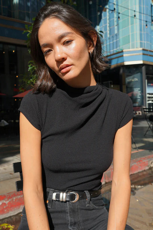 Woman wearing a black top mock-neck draped top
