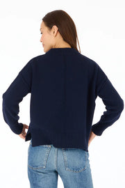 Back view of woman wearing navy blue mock-neck knitted sweater with "Peace + Love" embroidered