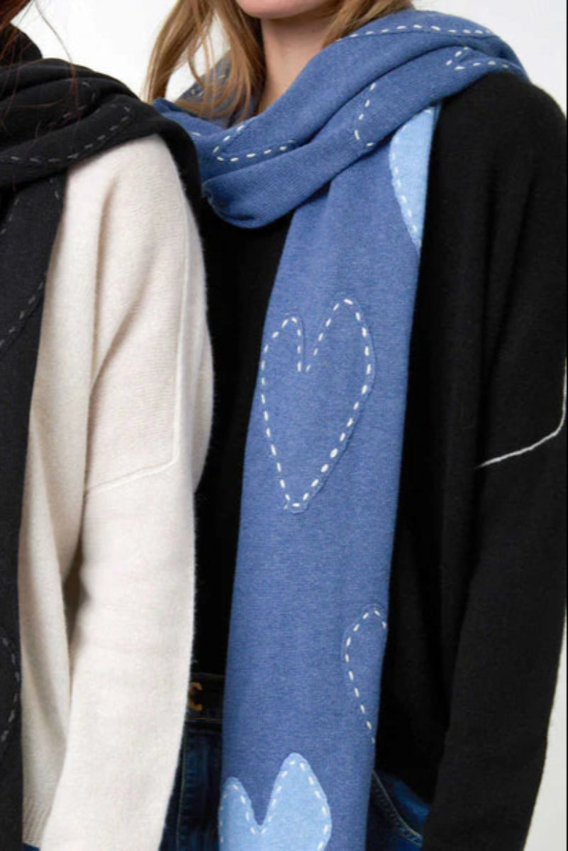 Woman wearing a blue scarf with imperfect heart patches and whipstitch detailing all over