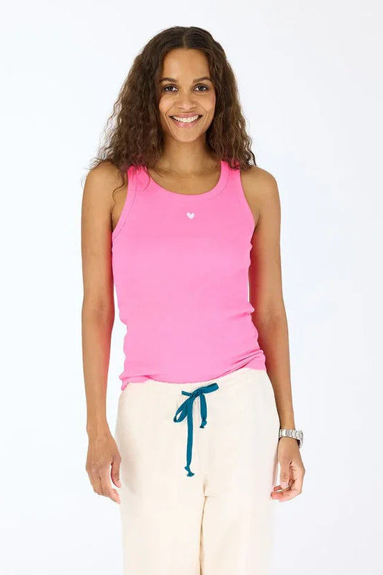 woman wearing a pink tank top with a white embroidered heart in the top middle of the chest