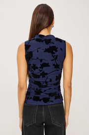 Back view of a woman wearing a sleeveless navy mesh top with a pattern of black roses