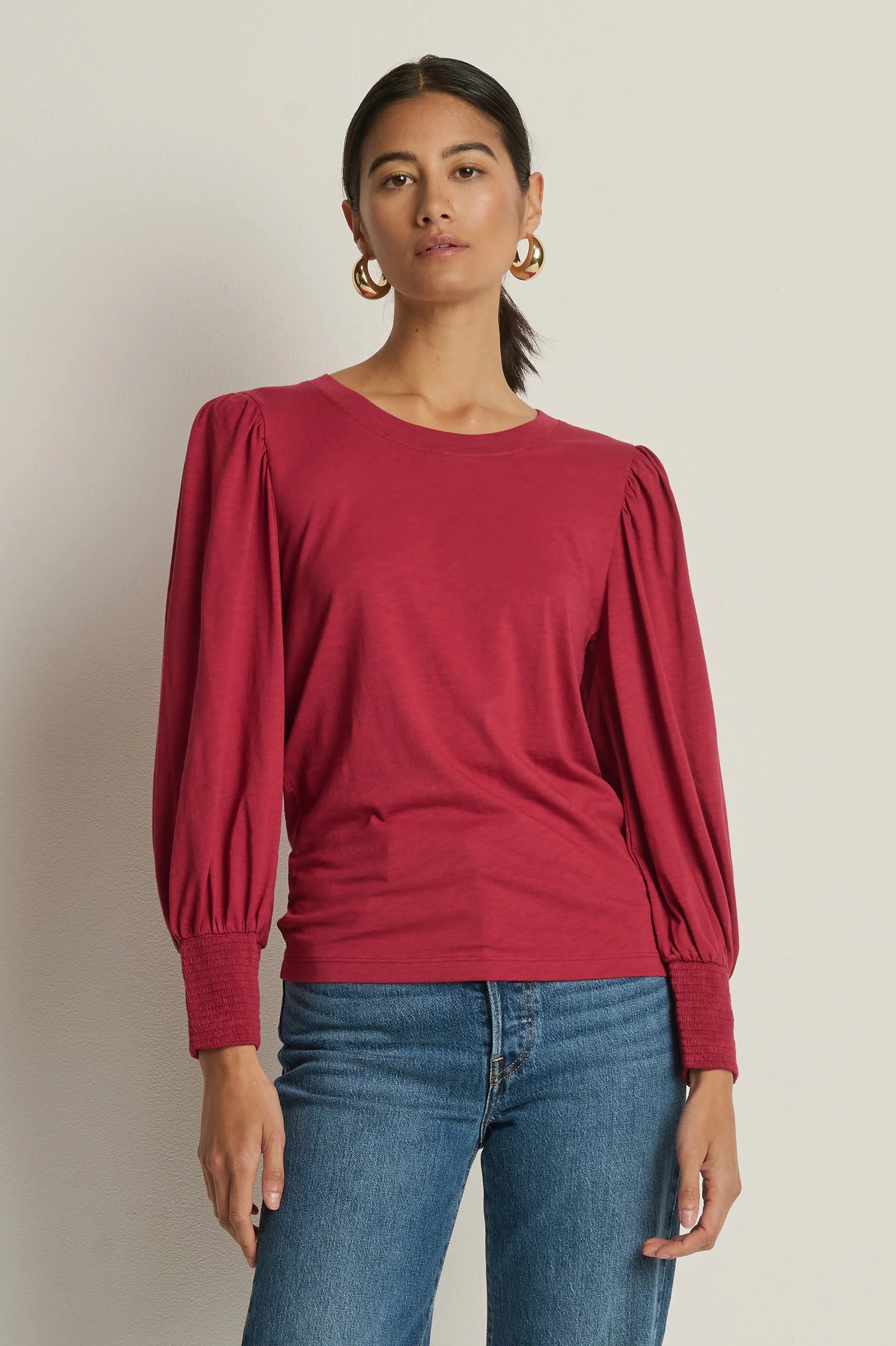 Woman wearing a red blouse with puffed and cuffed sleeves 