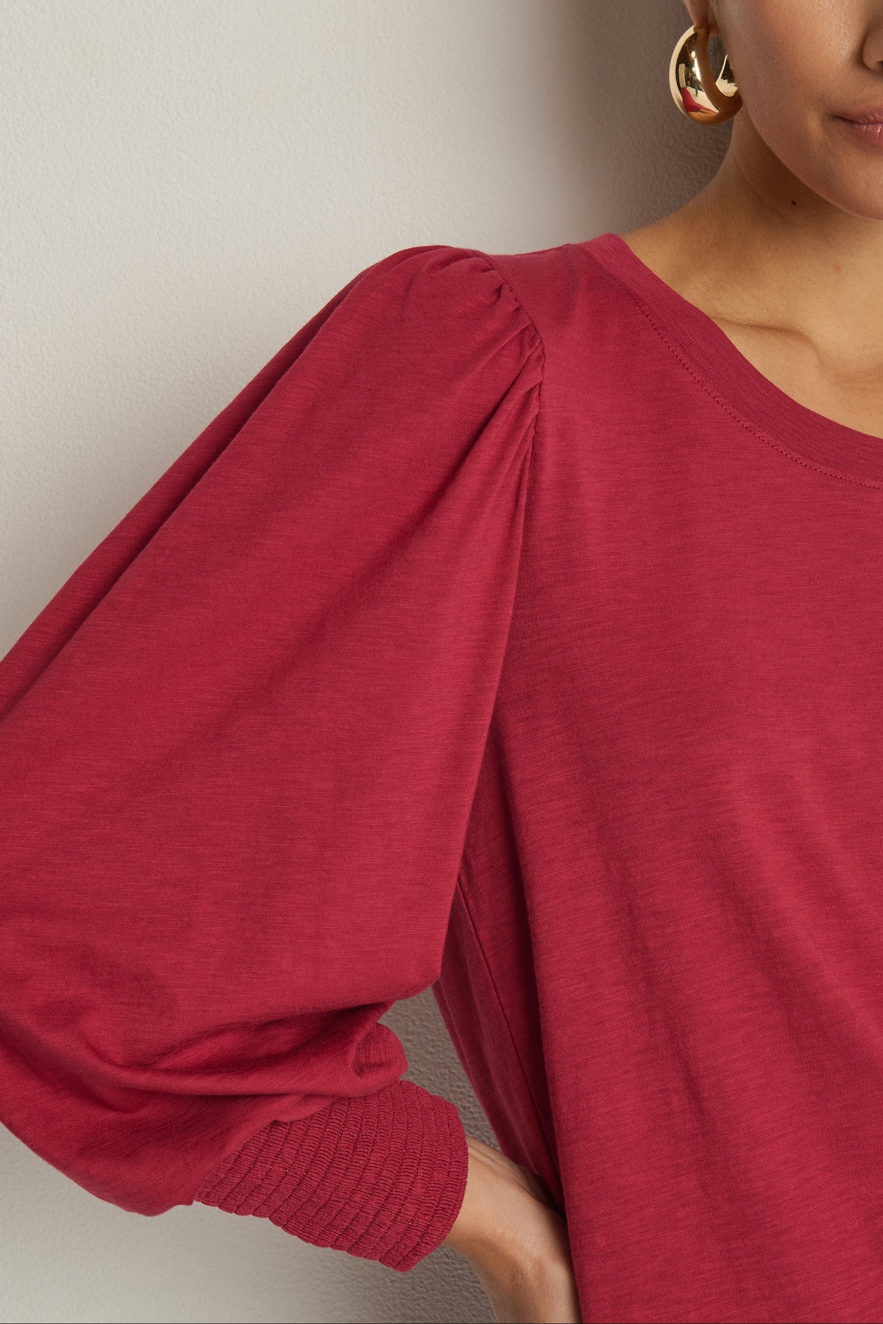 woman wearing a red top with cuffed and cuffed sleeves