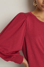 woman wearing a red top with cuffed and cuffed sleeves