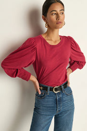 Woman wearing a red blouse with puffed and cuffed sleeves 