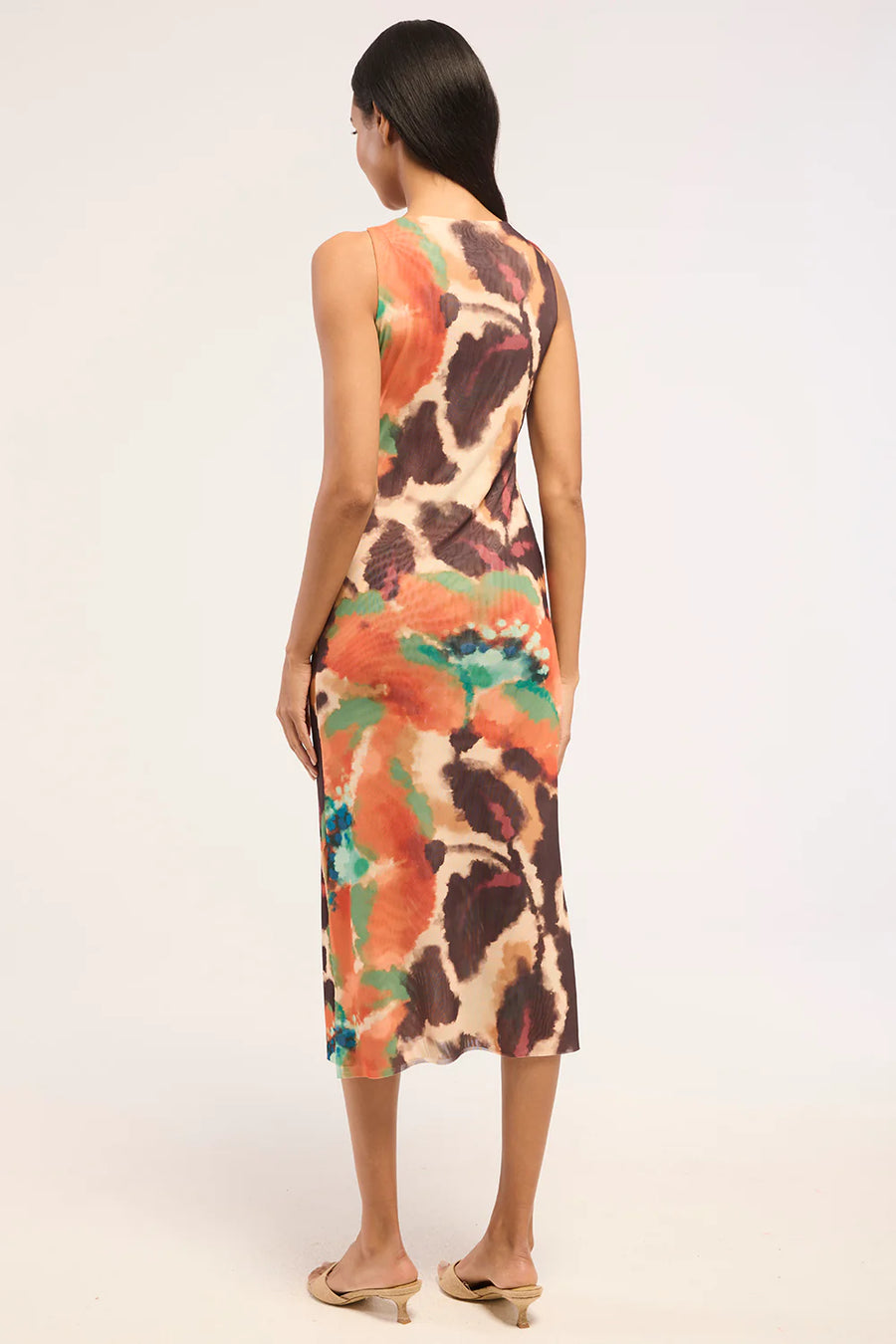 Woman wearing a patterned mesh dress with slit. 