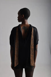 Back view of a woman wearing a high neck satin loose fitting blouse with bow  undone
