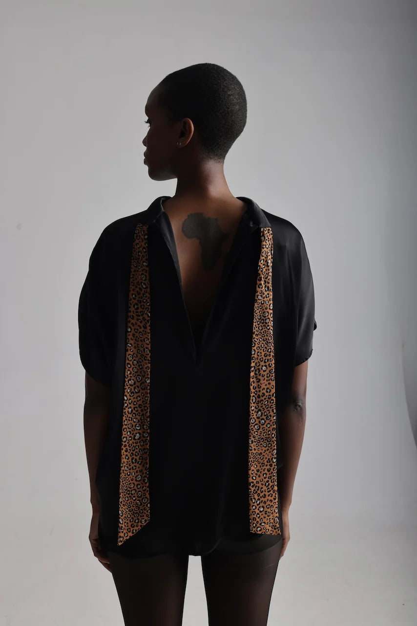 Back view of a woman wearing a high neck satin loose fitting blouse with bow  undone
