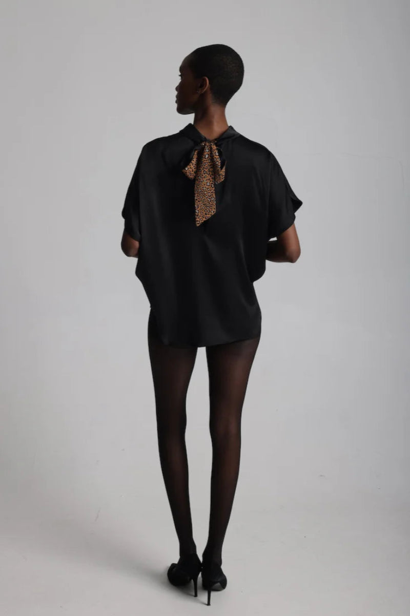 Back view of a woman wearing a high neck satin loose fitting blouse with bow  done up