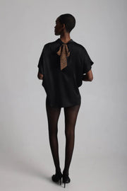 Back view of a woman wearing a high neck satin loose fitting blouse with bow  done up