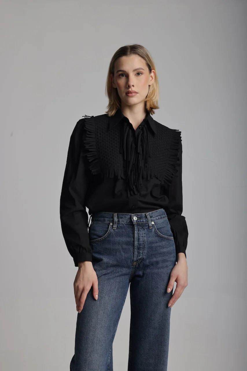 Front view of woman wearing a black blouse with fringe details