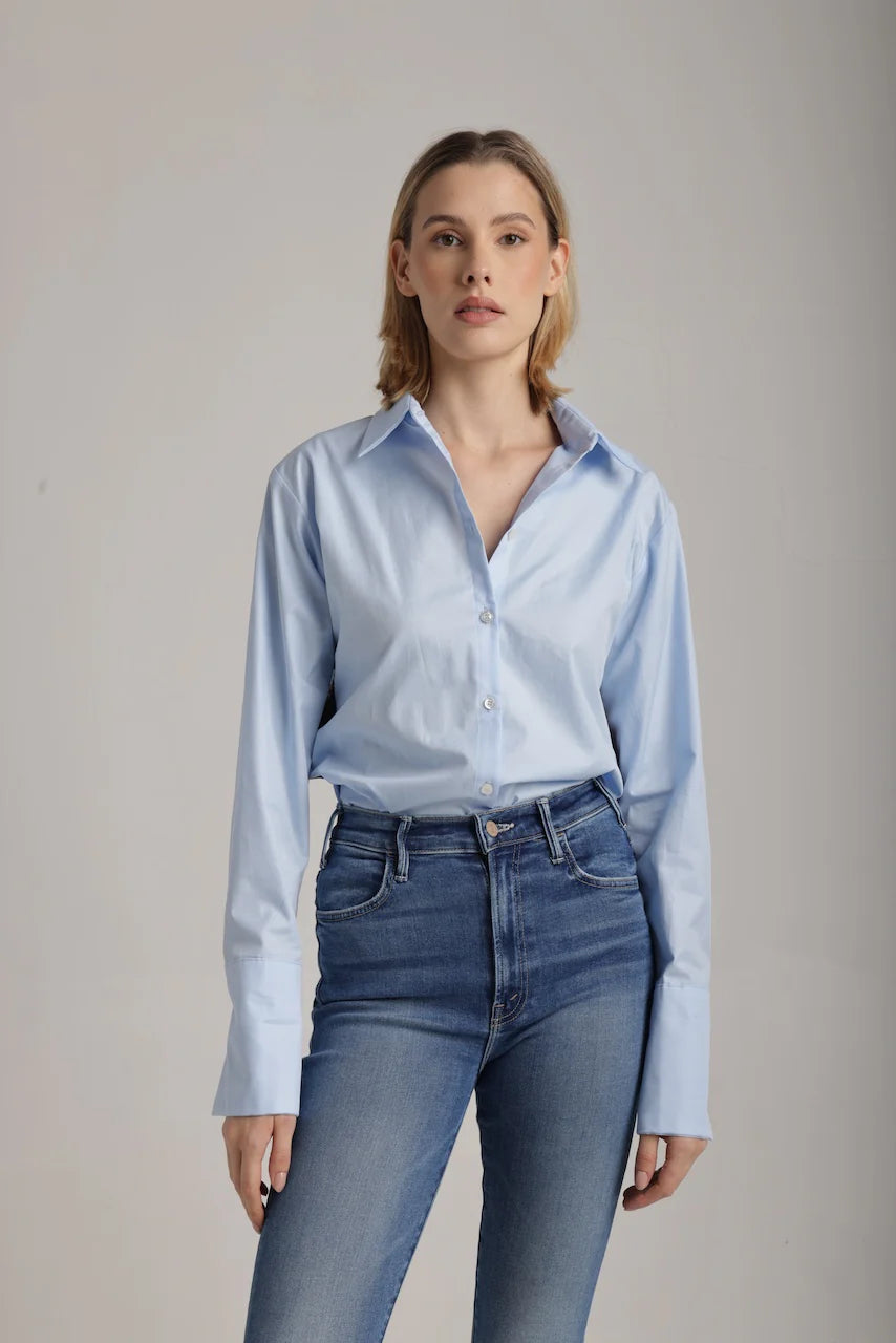 Front view of woman wearing a light blue shirt with red, navy and gold sequence stripes on the side