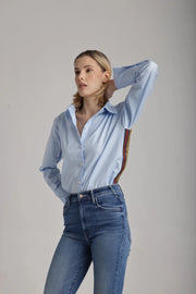 Side view of woman wearing a light blue shirt with red, navy and gold sequence stripes on the side