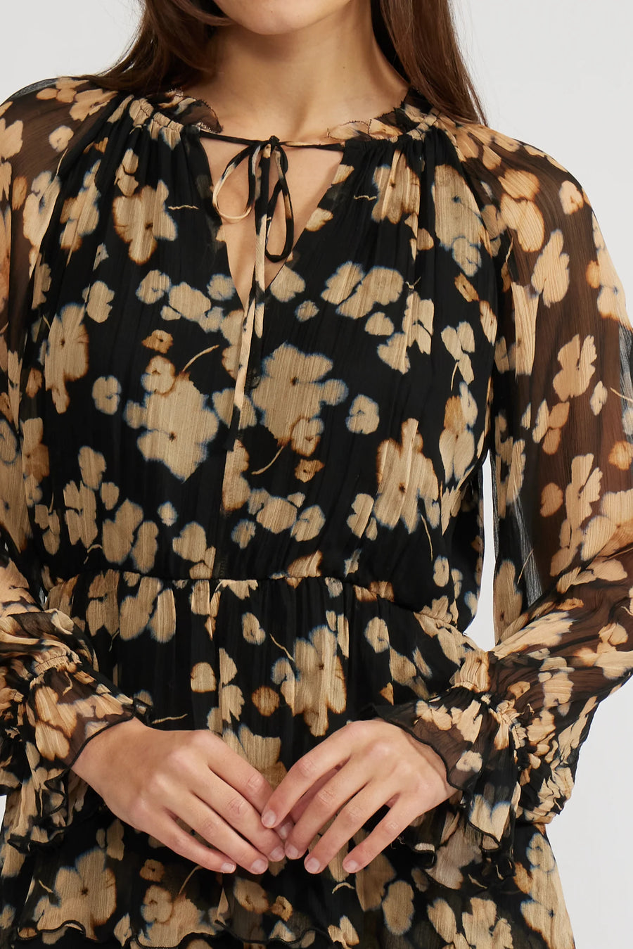 Close-up view of a woman wearing a mini black with beige flowers dress with long sleeves and knee-high boots