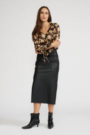Full body view  view of a woman wearing a sheer long sleeve floral blouse with a black skirt on a white background