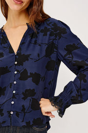 close-up of a  woman wearing a blue blouse with black roses and buttons