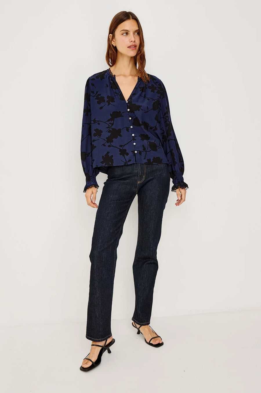 woman wearing a blue blouse with black roses and buttons and jeans