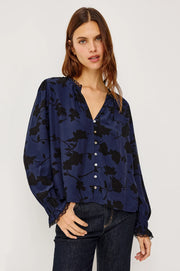 woman wearing a blue blouse with black roses and buttons