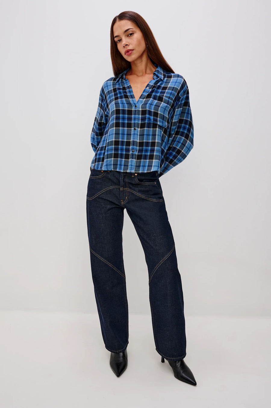 woman wearing blue plaid button up and dark blue jeans
