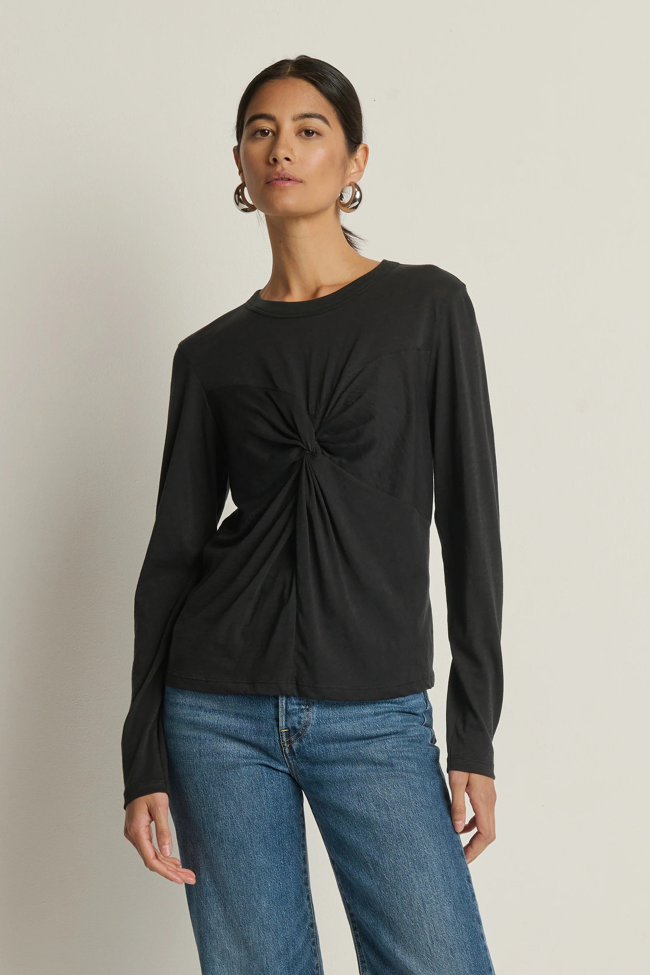 woman wearing a long sleeve black top with a twist detail in the chest