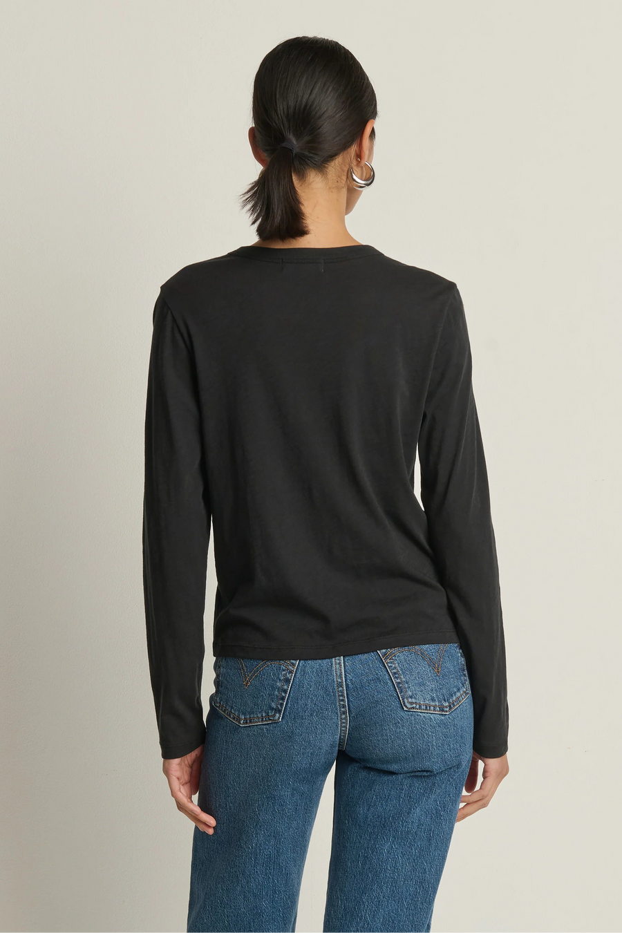 woman wearing a long sleeve black top with a twist detail in the chest
