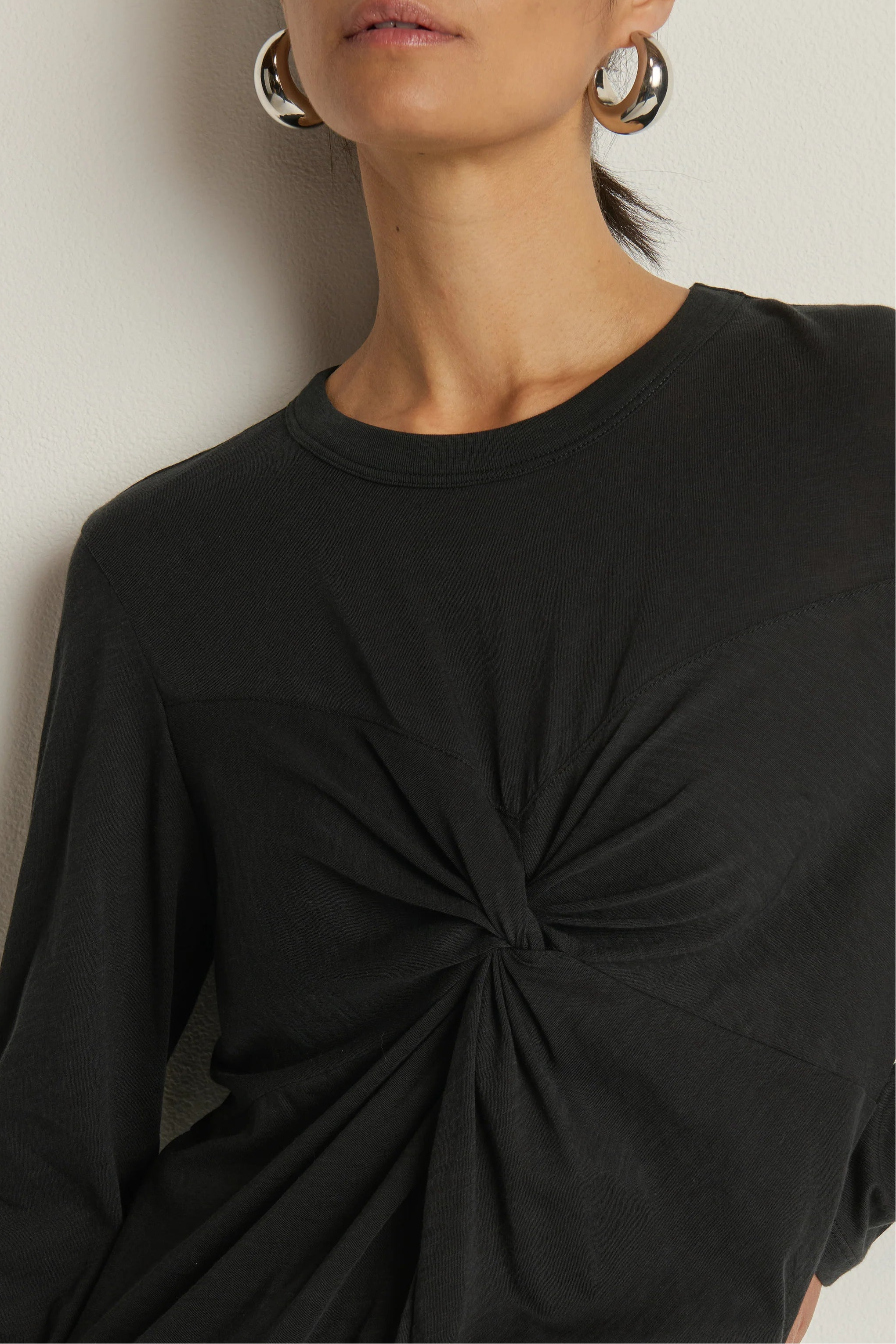 close-up of a long sleeve black top with a twist detail in the chest