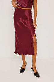 Burgundy satin skirt worn by a person on a white background
