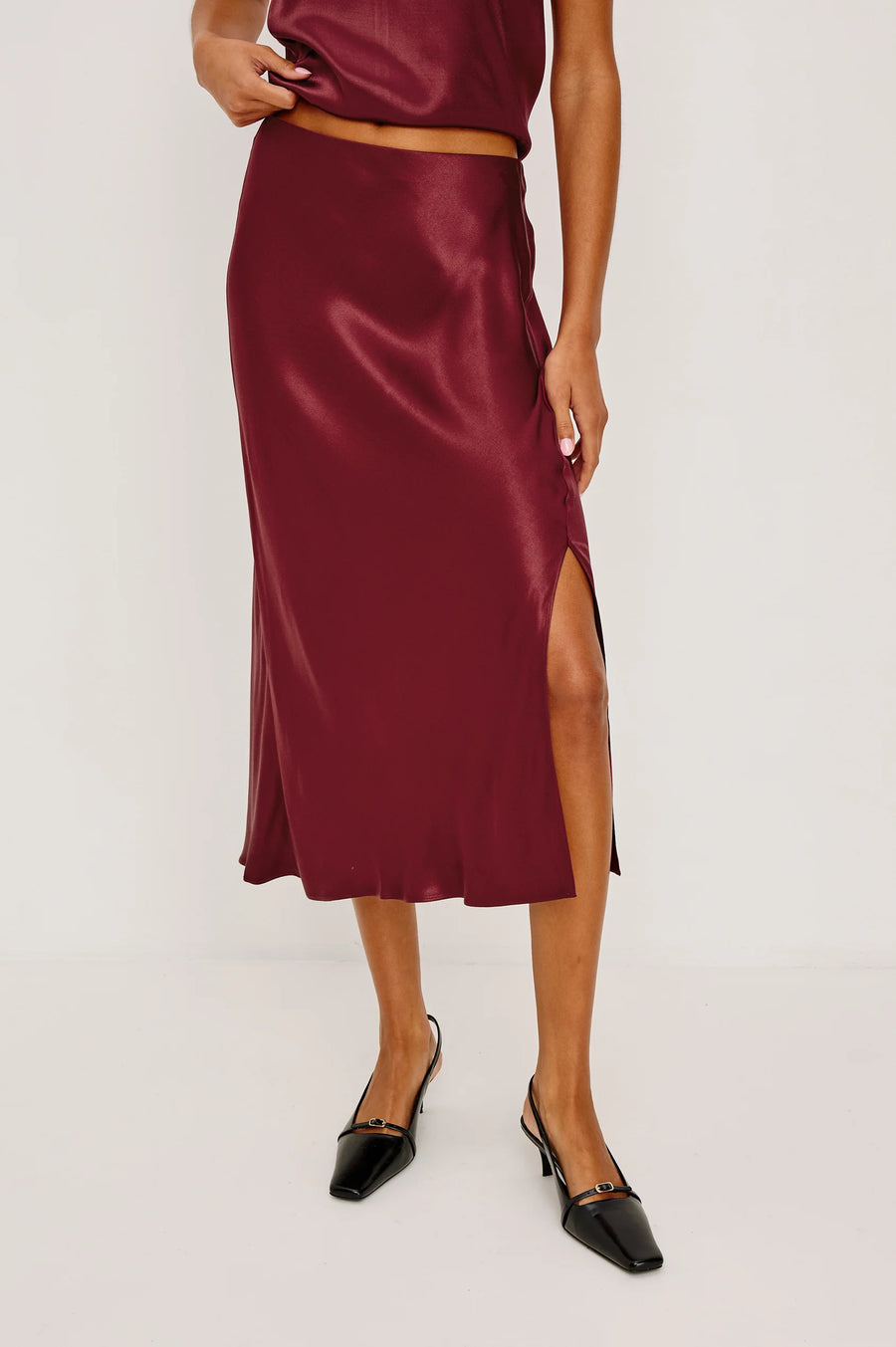 Burgundy satin skirt worn by a person on a white background