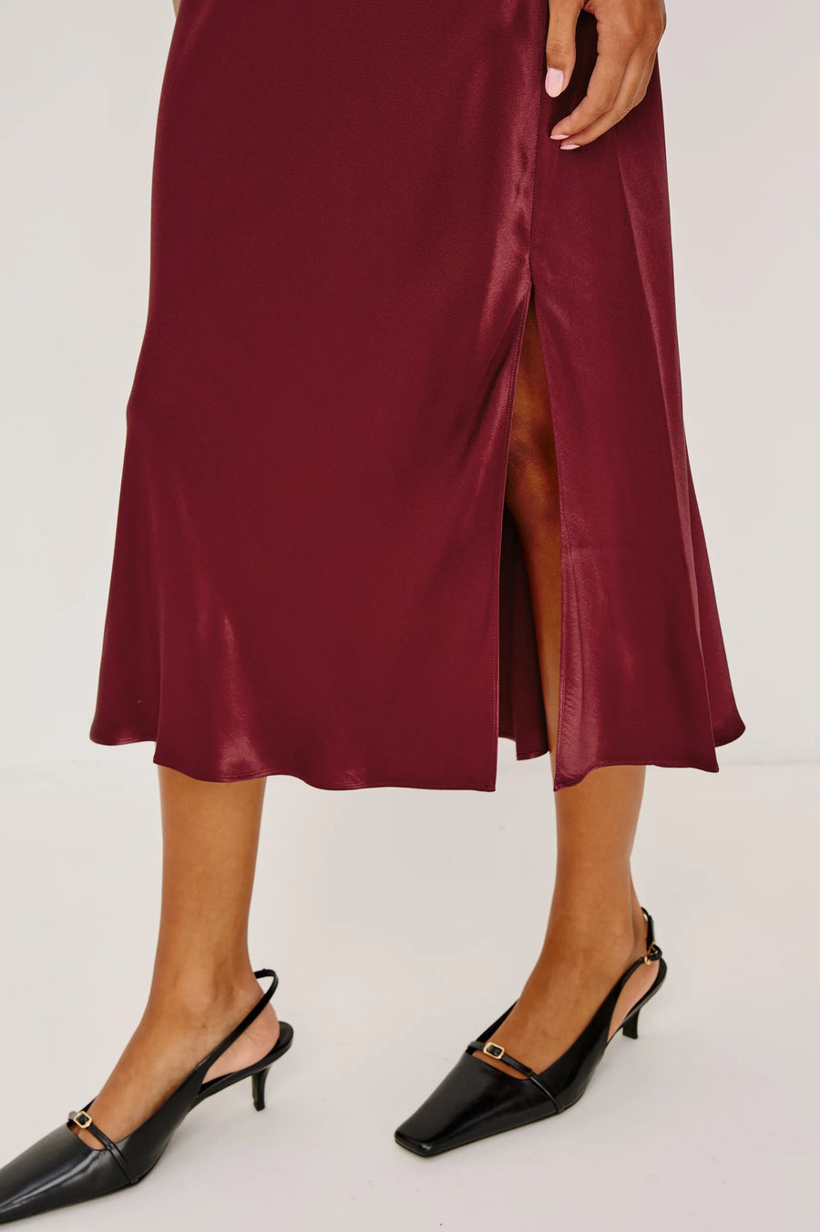 Maroon satin skirt with a high slit worn by a person on a white background