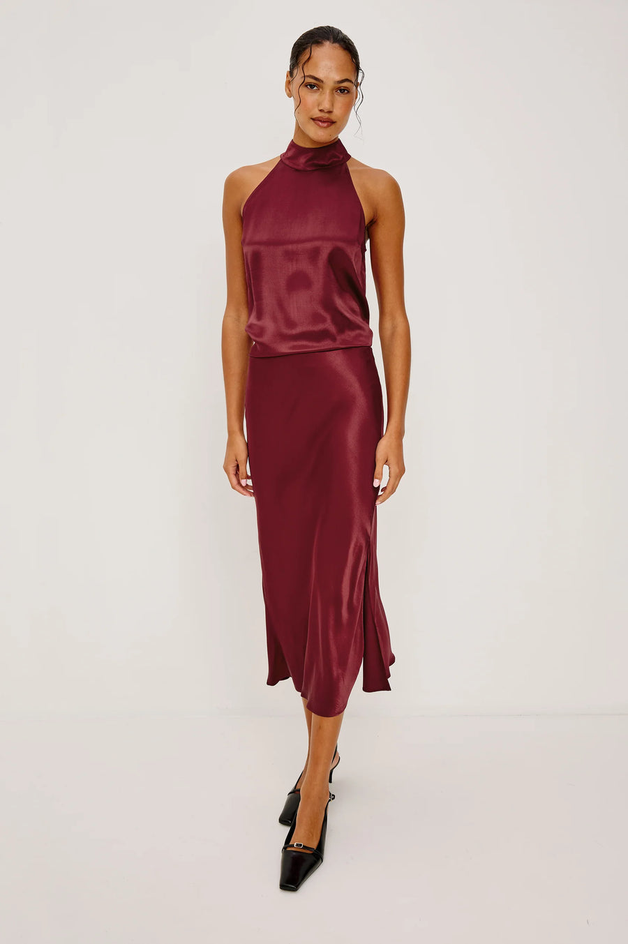 Woman wearing a burgundy satin dress on a white background
