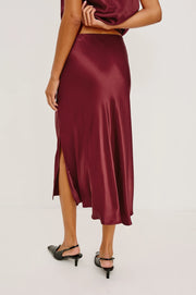 Burgundy satin skirt worn by a person on a white background
