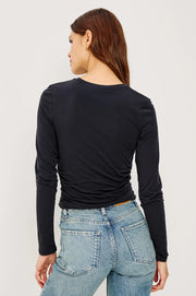 Person wearing a black long-sleeve top and blue jeans on a white background