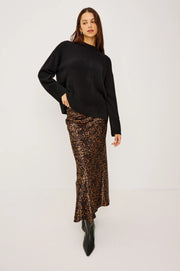 woman wearing a black cashmere blend sweater and a leopard dress underneath 