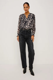 woman wearing a tiger stripped patterned blouse and black barrel jeans