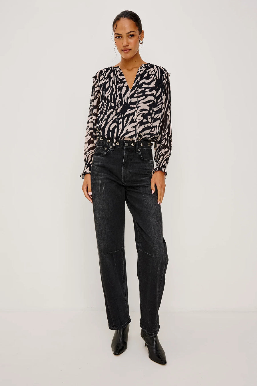 woman wearing a tiger stripped patterned blouse and black barrel jeans