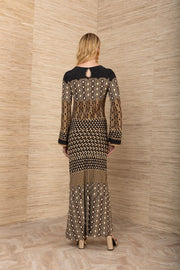 Back view of woman wearing a black, brown and mustard yellow patterned maxi jersey long sleeve dress.