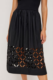 Close up of  a black cotton dress with cut outs in the bottom