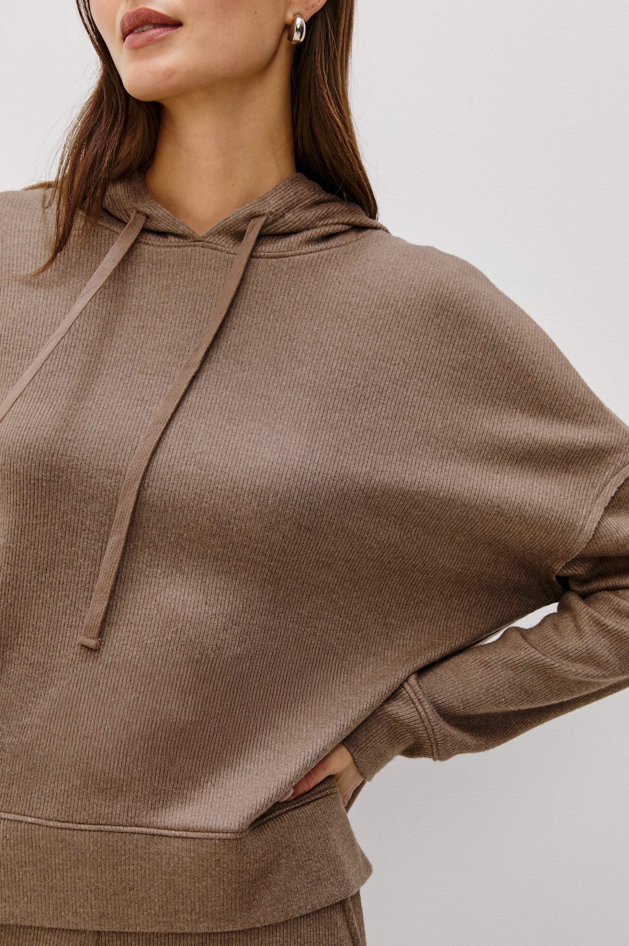 Woman wearing a matching set of light brown hoodie and pants on a white background