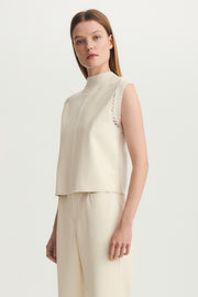Side view of a woman wearing a mix media mock neck tank top