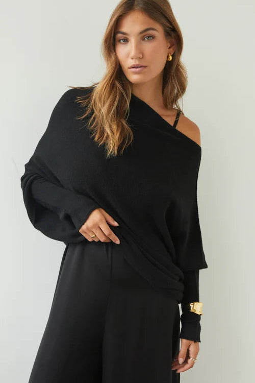 Woman wearing a black one-shoulder dress against a white background