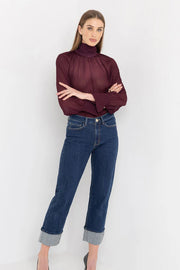 Woman wearing a burgundy sweater and blue jeans on a white background